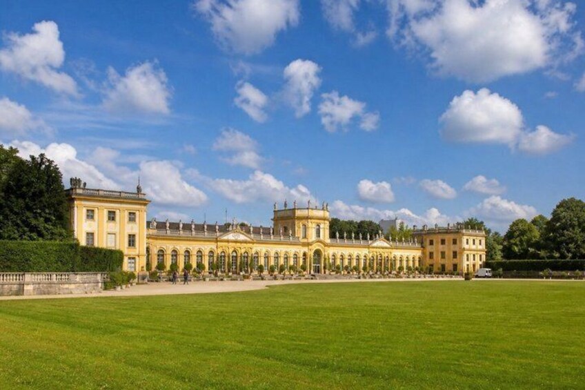A grand palace with symmetrical architecture, a large lawn, and a clear blue sky with clouds. 4