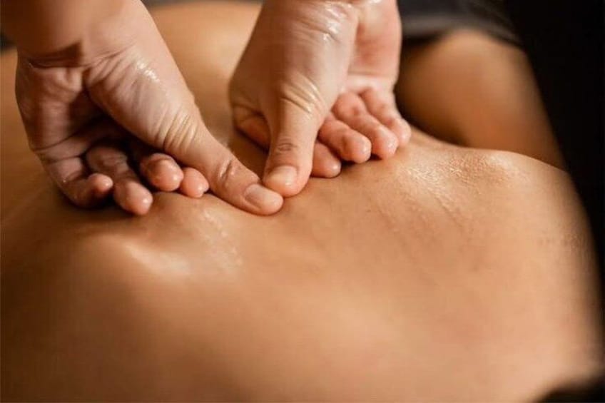 A close-up of hands performing a massage on a person's back. 3