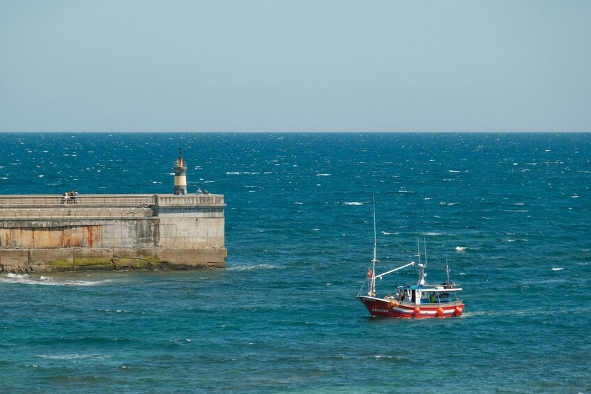A lighthouse, a pier, and a boat on a calm sea. 2