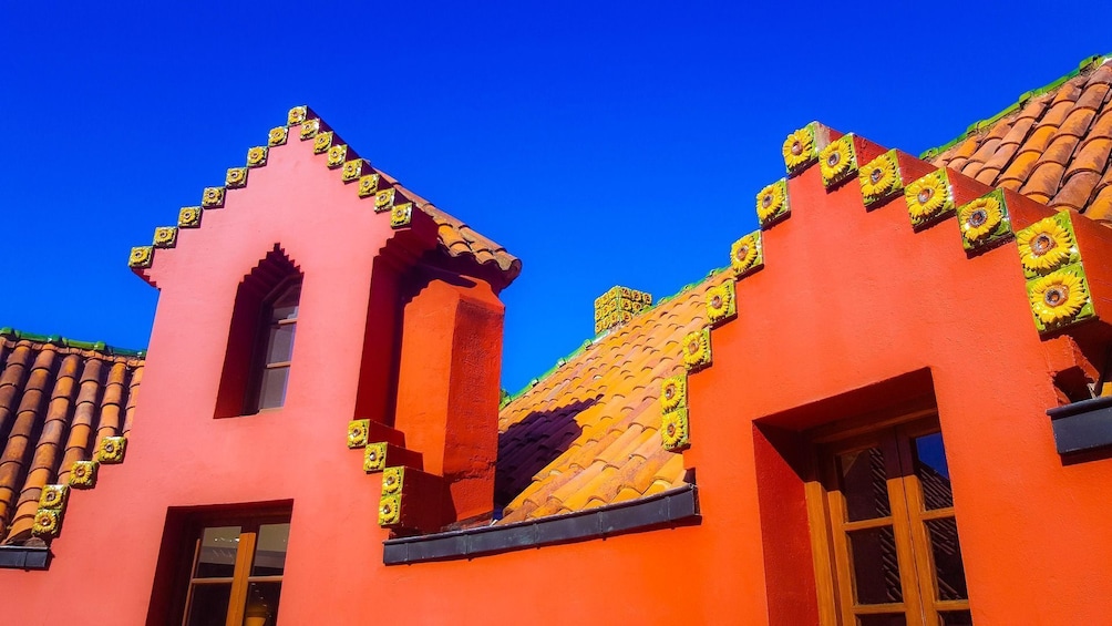 A brightly colored building with a red facade and yellow decorative tiles on the roof. 4