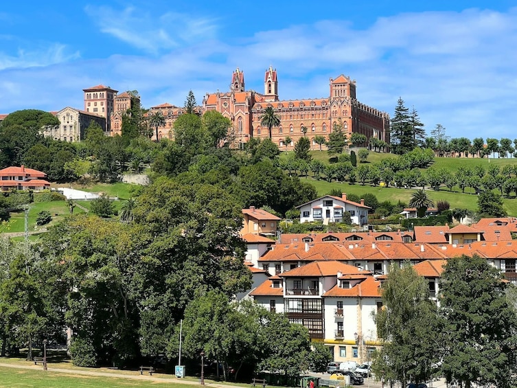 A historic castle on a hill with surrounding residential buildings and lush greenery. 3