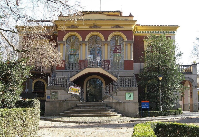 A historic building with a red facade, arched windows, and a balcony. 3
