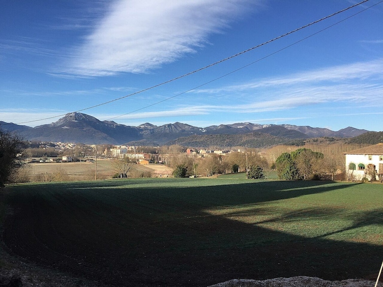 A rural landscape with a clear sky, distant mountains, and scattered buildings. 2