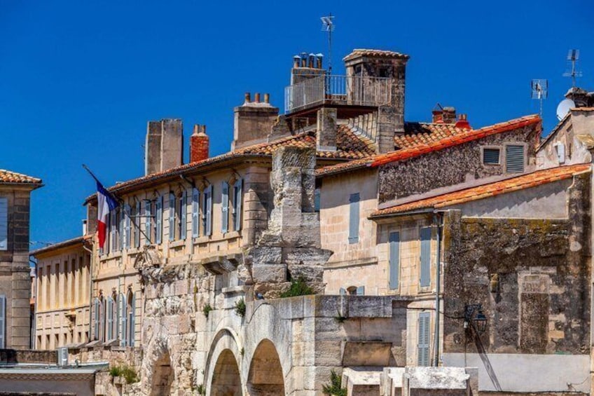 A historic stone building with a red-tiled roof, a flag, and an arched entrance. 4