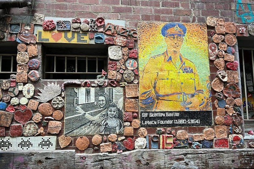 A mosaic wall with various tiles and a portrait. 5