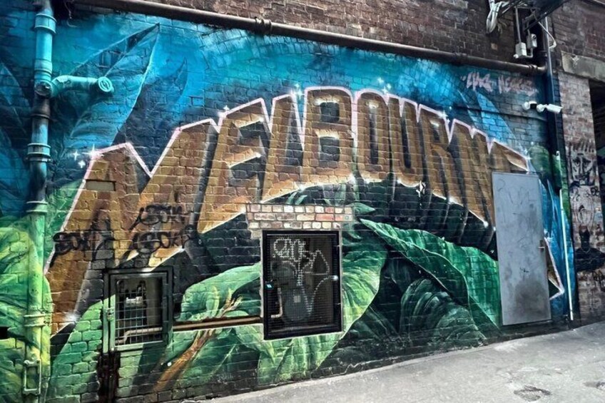 A mural with the word 'MELBOURNE' and a brick wall. 2