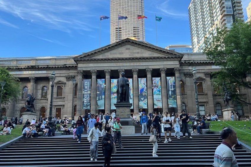 A large public building with columns and a statue in front. 3