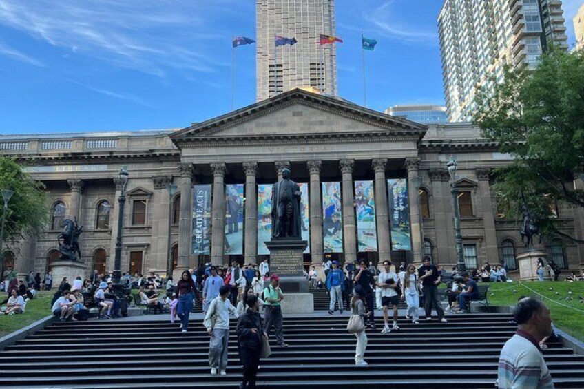 A large public building with columns and a statue in front. 3