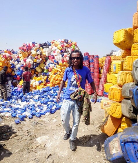 A person standing in a pile of colorful plastic containers, with more containers stacked in the background. 4