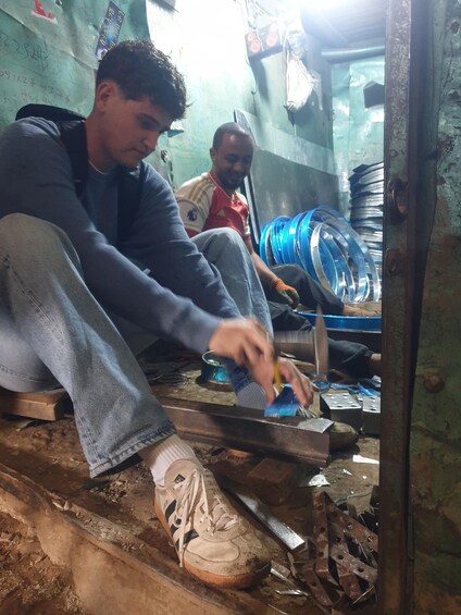 A person working with metal sheets on a table in a workshop. 3