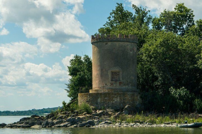 A stone tower by a lake, surrounded by trees and rocks. 4