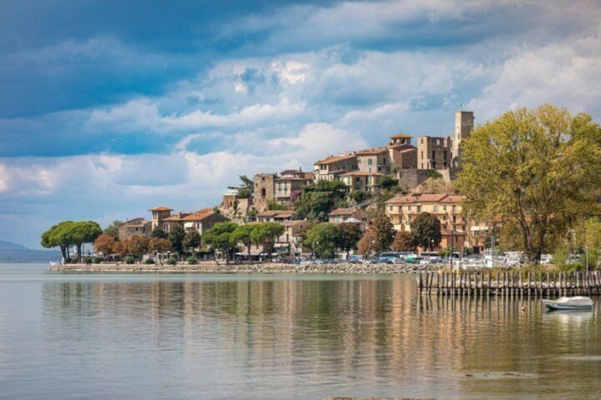 A lakeside town with historic buildings, a dock, and a boat. 1