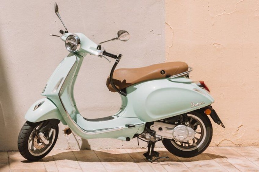 A light blue Vespa scooter parked against a wall. 3