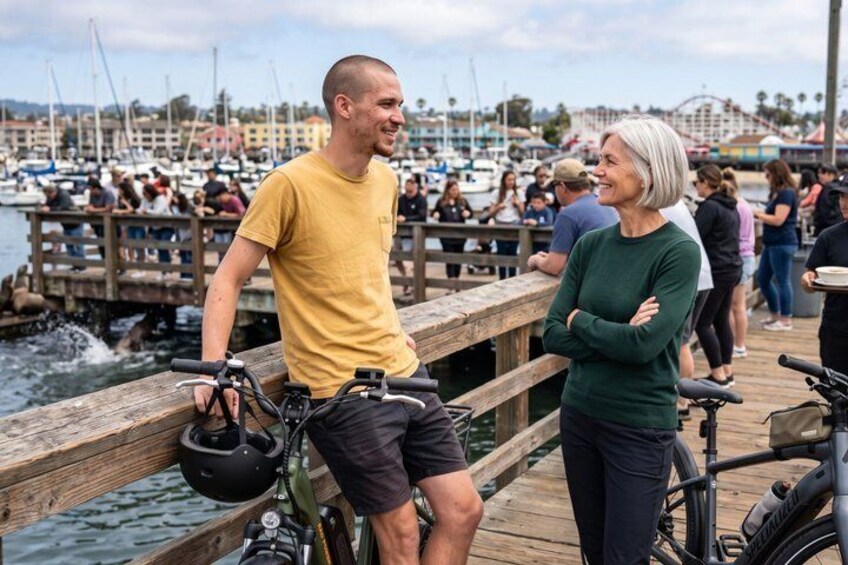 A wooden pier with people, bicycles, and a marina in the background. 5