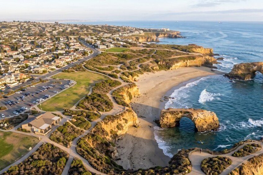 A coastal town with a prominent rock arch, sandy beaches, and a residential area. 2