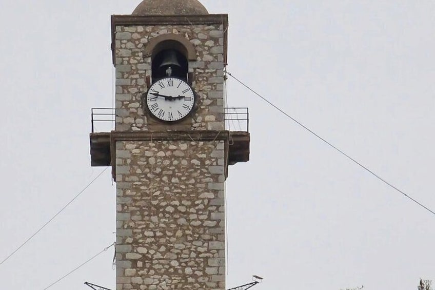 A stone clock tower with a bell and a clock face. 4