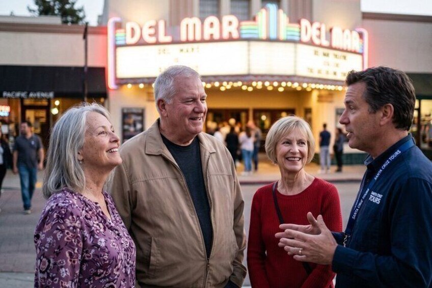 A theater marquee, a sidewalk, and people standing and conversing. 1