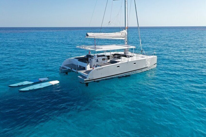 A white sailboat with a cabin and a canopy, floating on clear blue water. 5