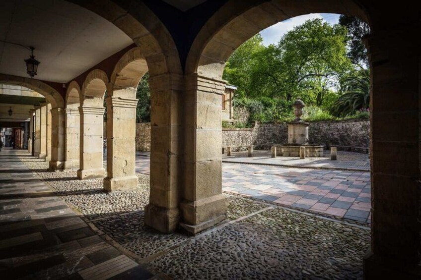 An ancient stone courtyard with arches, a fountain, and a tiled floor. 4