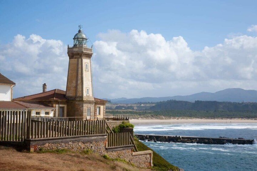 A lighthouse, a wooden fence, and a beach with waves. 1