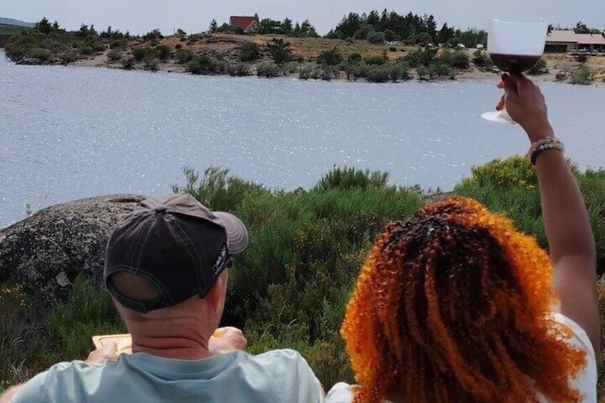 Two people sitting by a lake with a house in the background. 4