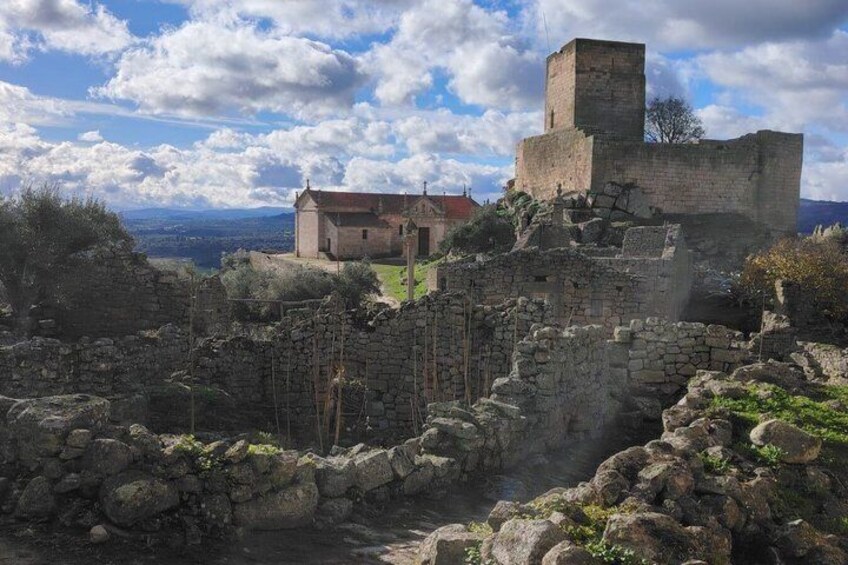 Ancient ruins with stone walls and a building in the background. 1