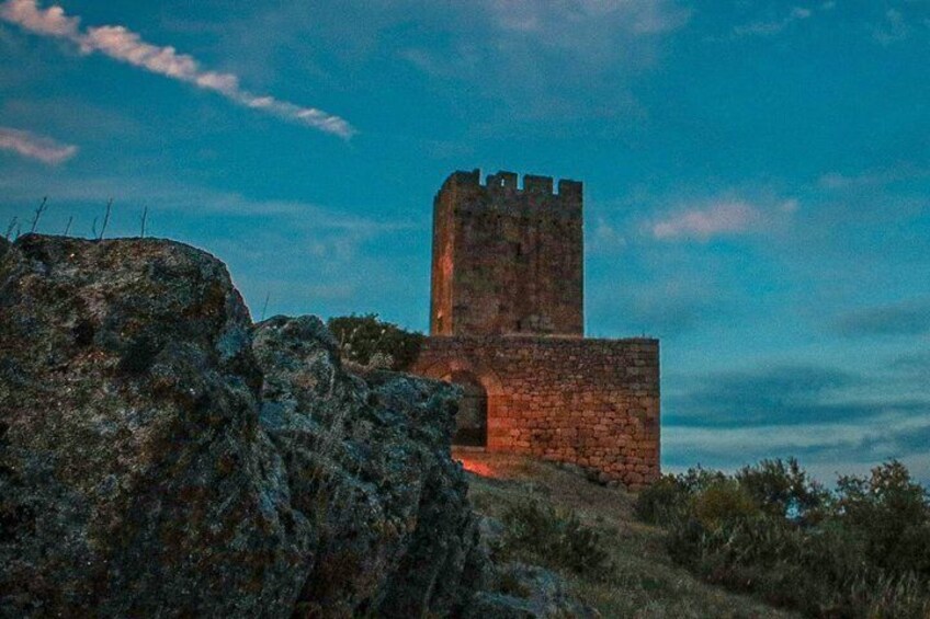 A stone tower with a flat top, surrounded by rocky terrain and sparse vegetation. 2