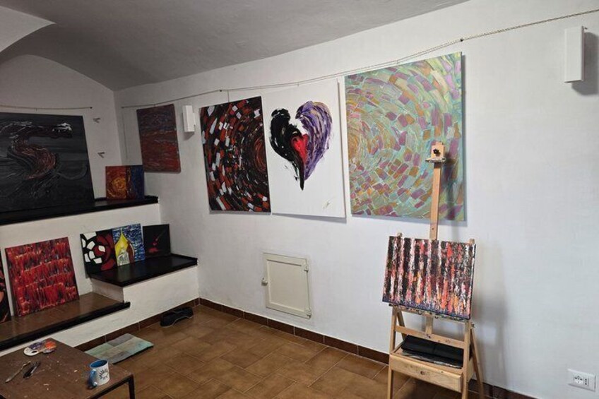 An art gallery with various paintings on the walls and a wooden easel with a canvas. 1
