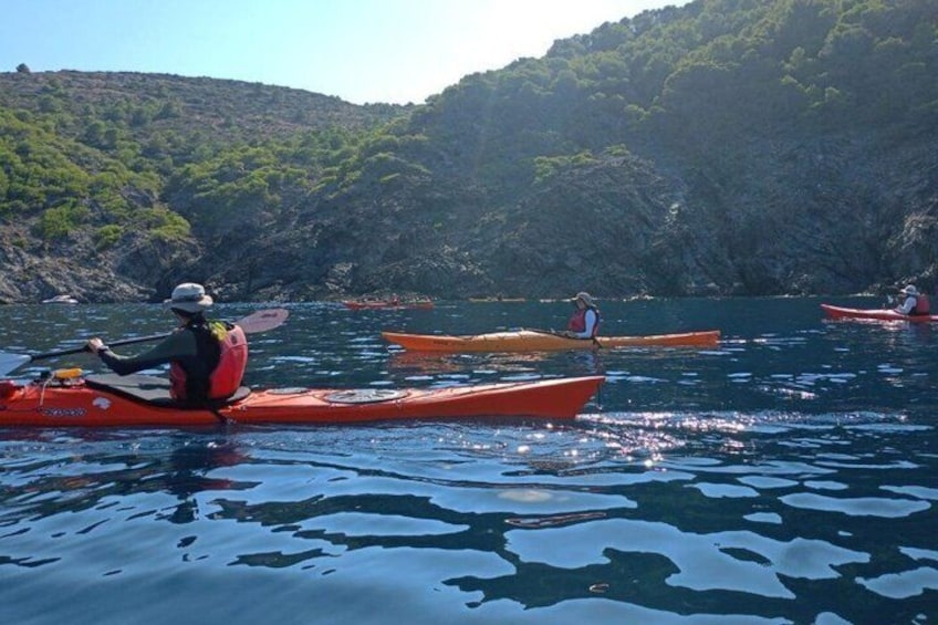 People kayaking on a calm body of water surrounded by rocky cliffs. 1