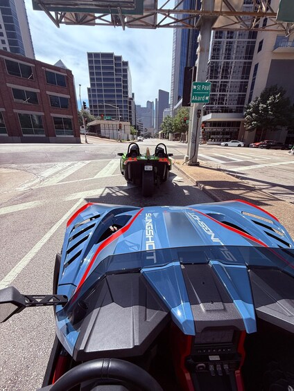 A futuristic vehicle with a blue and red design, a cityscape with tall buildings, and a street intersection. 4