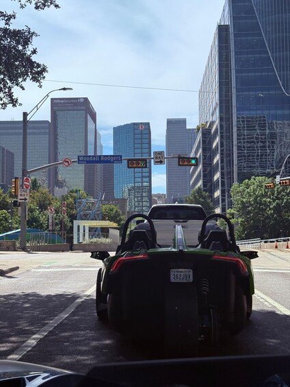 A convertible car at an intersection with a city skyline in the background. 2