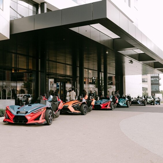 A modern building with a glass facade and a row of sports cars parked in front. 1