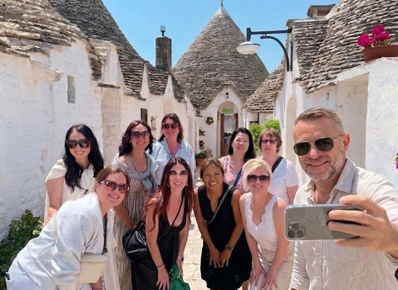 A group of people in a narrow street with white buildings and conical roofs. 4