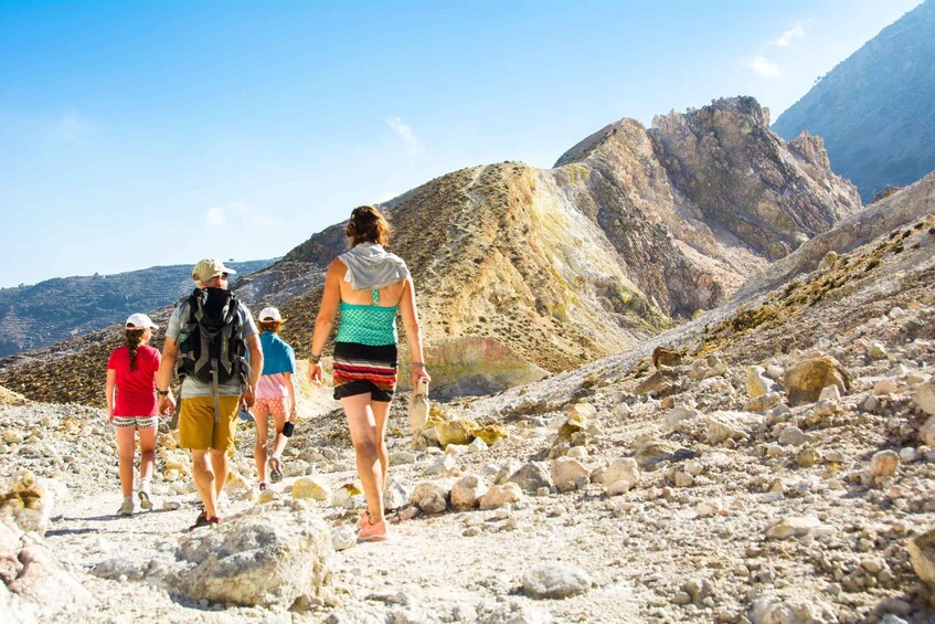 A group of hikers on a rocky trail with mountains in the background. 2