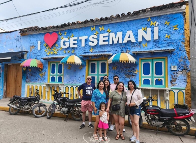 A group of people posing in front of a building with a mural that says 'I ♥ GETSEMANI' and a blue and yellow color scheme. 1