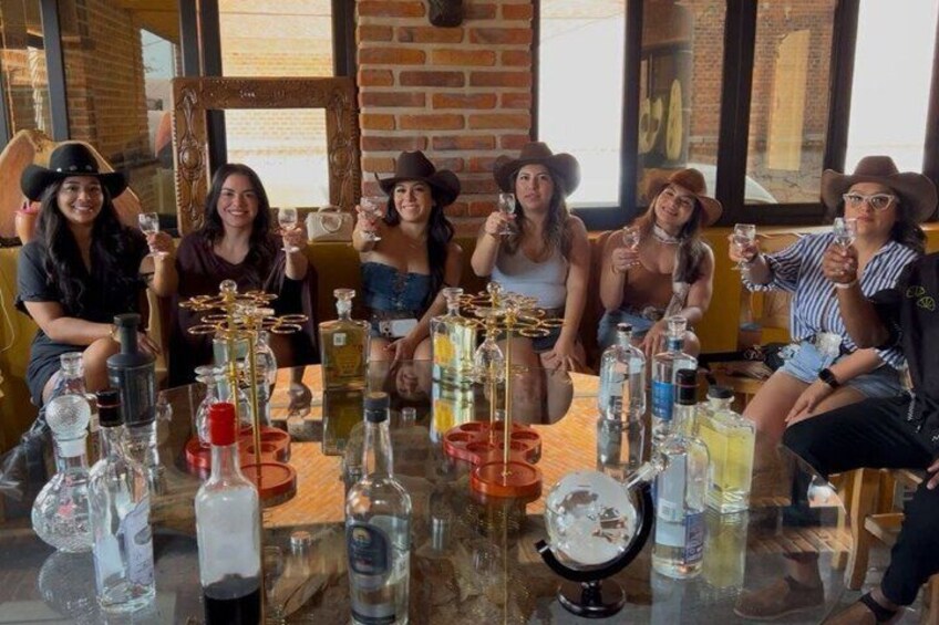 A group of people sitting at a table with various bottles and glasses. 3