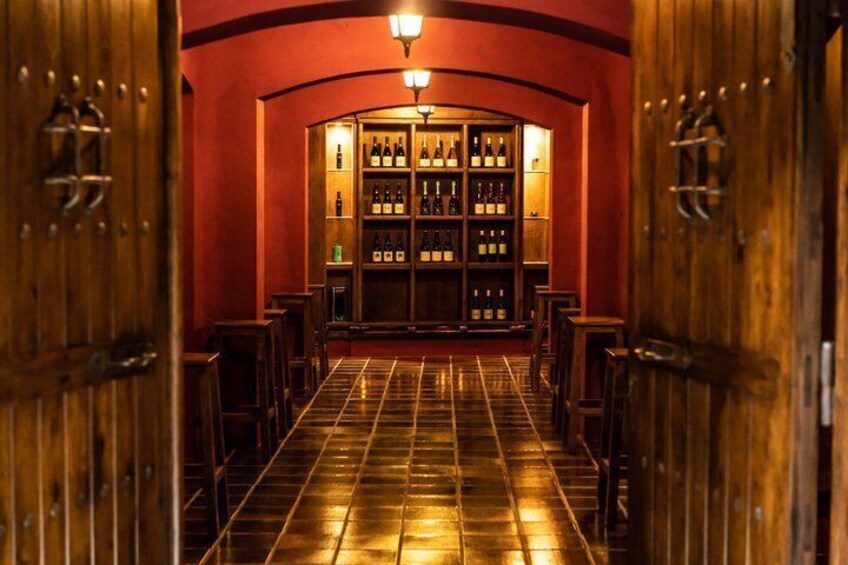 A bar with wooden doors and a tiled floor leading to a shelf of bottles. 4