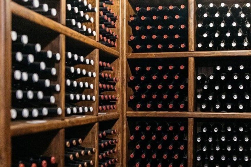 A wooden wine rack with multiple rows of wine bottles. 5