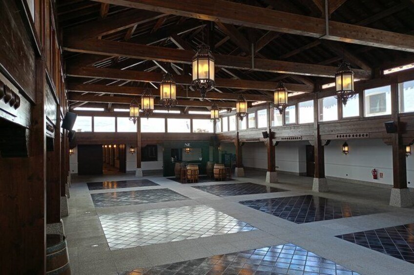 A spacious indoor area with wooden beams, tiled flooring, and hanging lanterns. 2