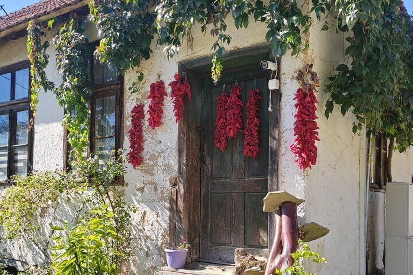 A building with a rustic facade, a wooden door, and red chili peppers hanging on the wall. 3
