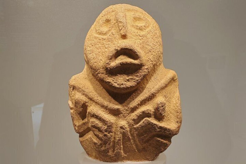A stone sculpture with a carved face and abstract patterns. 5