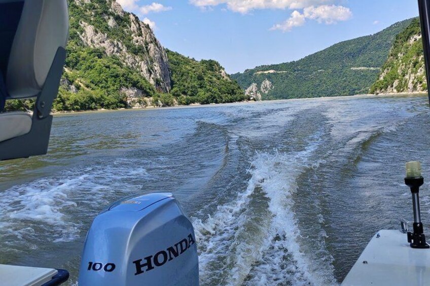 A boat with a Honda outboard motor on a river surrounded by green hills. 3