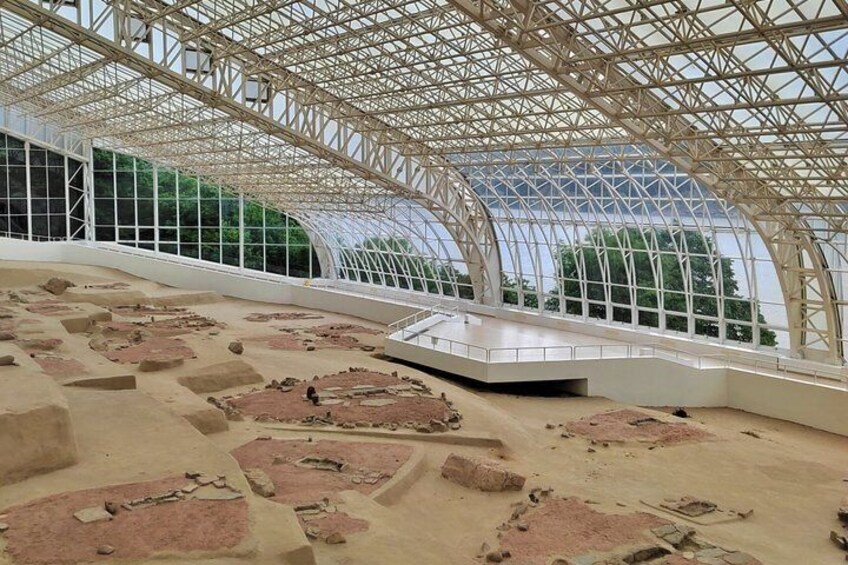 An indoor archaeological site with exposed ruins and a glass ceiling. 4