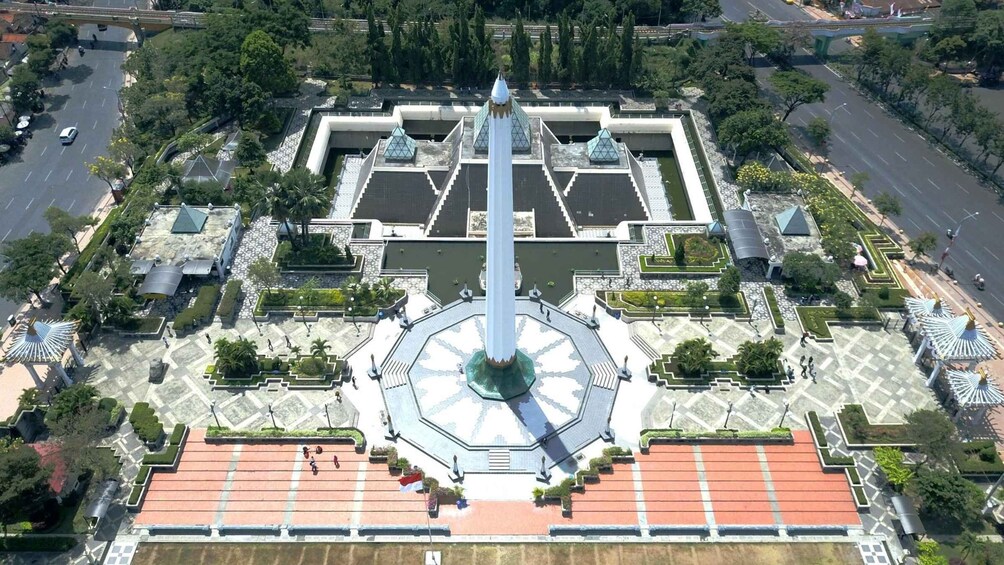 An aerial view of a square with a central monument, surrounded by greenery and pathways. 1