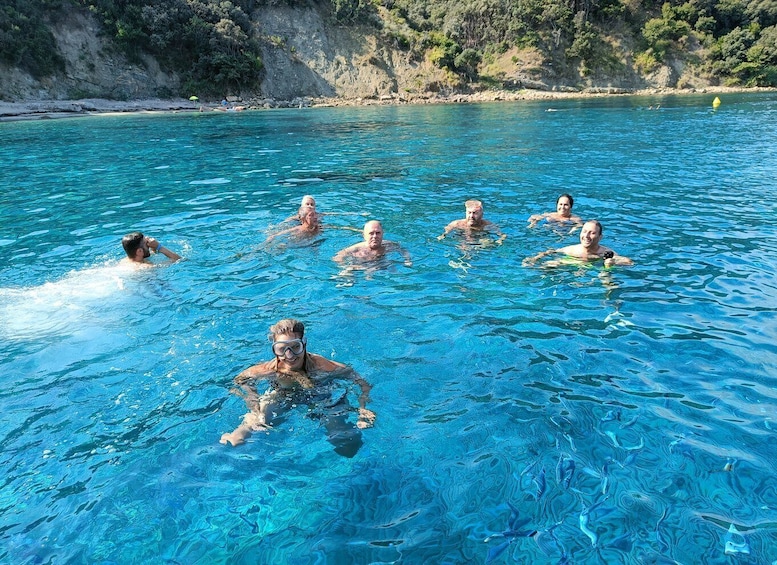 A group of people swimming in a clear blue pool surrounded by a rocky coastline. 2