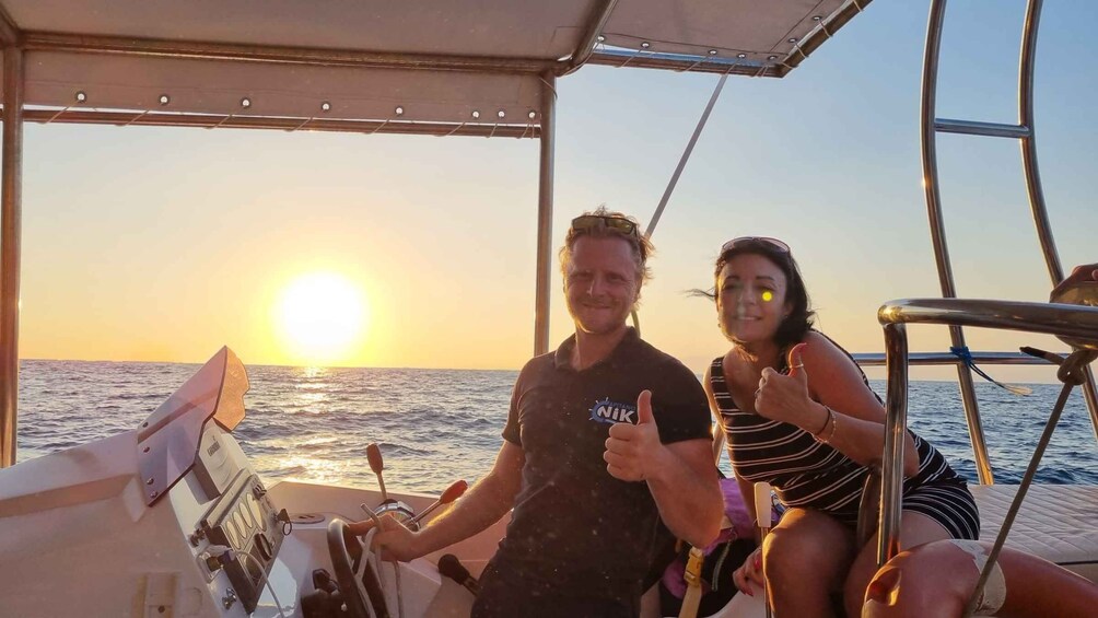 A boat with two people, one giving a thumbs-up, and the sun setting in the background. 5