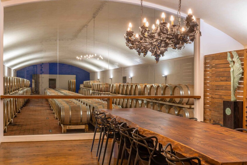 A wine cellar with wooden barrels, a wooden table, chairs, and a chandelier. 4