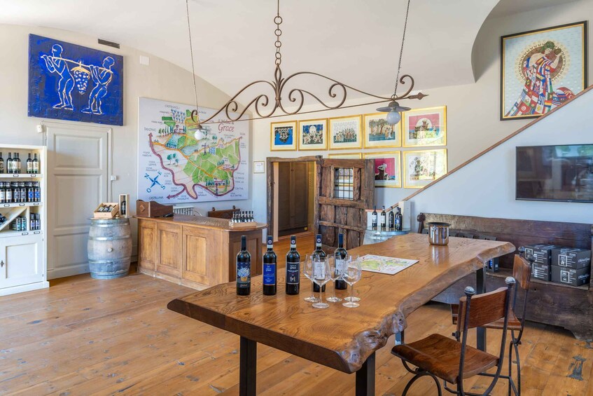 A wooden bar with wine bottles and glasses, a map on the wall, and various framed pictures. 1