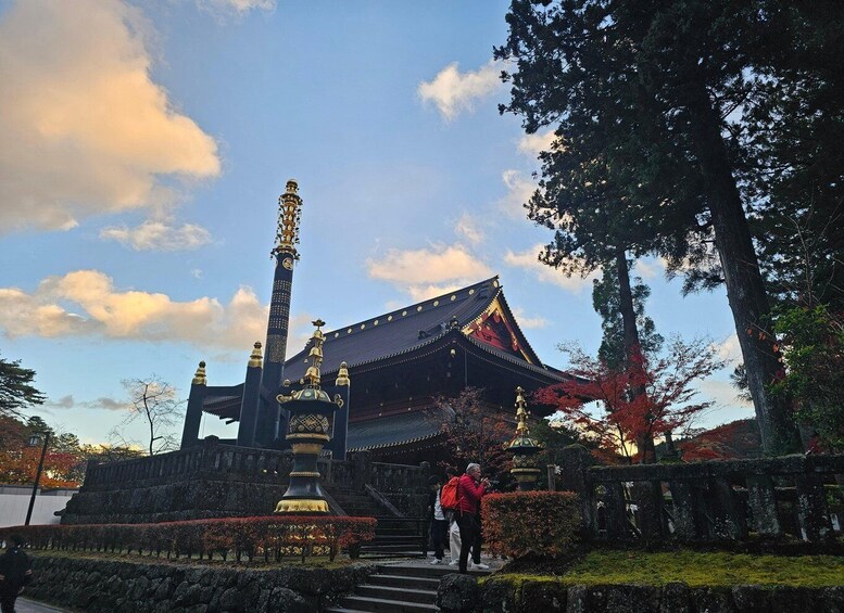 A traditional Japanese building with a prominent pagoda, surrounded by autumn foliage and a stone lantern. 2