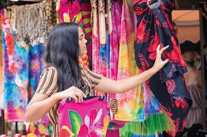 A person examining colorful fabrics at a market stall. 3